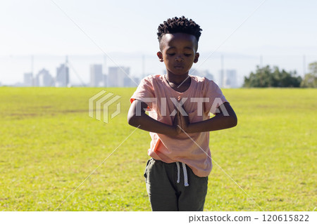Practicing yoga, african american boy meditating outdoors on grass, focusing on mindfulness Practicing yoga, african american boy meditating outdoors on grass, focusing on mindfulness 120615822