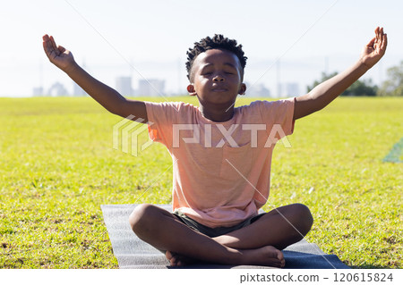 Meditating on yoga mat, african american boy practicing mindfulness outdoors in school setting Meditating on yoga mat, african american boy practicing mindfulness outdoors in school setting 120615824