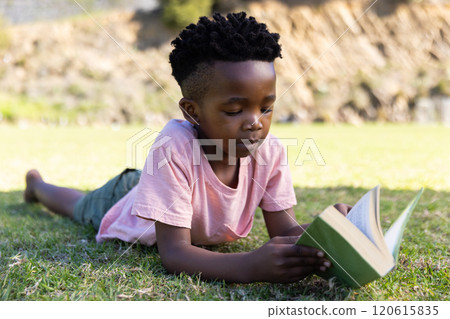 Outdoors, Reading book, african american boy lying on grass outside, enjoying leisure time 120615835