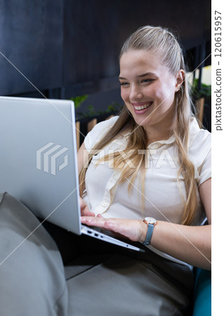 Smiling woman using laptop while working in office 120615957