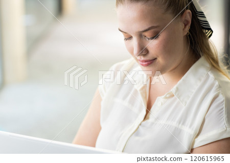 Working on laptop, woman focusing on task in modern office setting Working on laptop, woman focusing on task in modern office setting 120615965