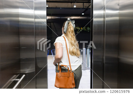 Exiting elevator, woman with handbag walking into modern office building 120615976