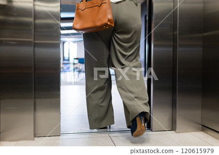 At office, Walking out of elevator, woman carrying brown handbag in business attire At office, Walking out of elevator, woman carrying brown handbag in business attire 120615979