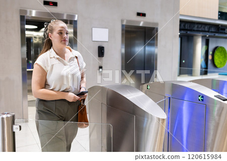 Entering office building, woman using access card at security turnstile Entering office building, woman using access card at security turnstile 120615984