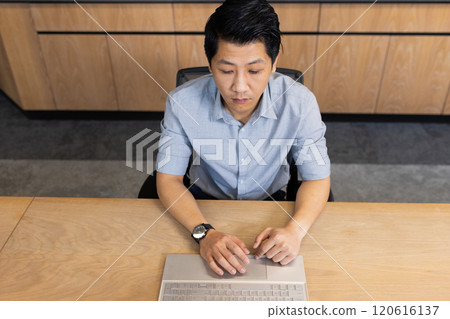 Working on laptop, asian man in office focusing on business tasks at desk 120616137