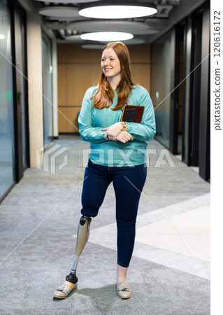 Walking in office, woman with prosthetic leg holding tablet and smiling 120616172