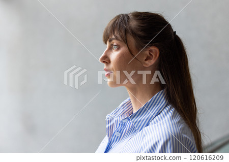 Side profile of woman in striped shirt looking thoughtfully into distance 120616209