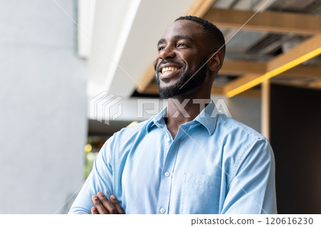 Smiling african american man in blue shirt standing confidently in modern office environment Smiling african american man in blue shirt standing confidently in modern office environment 120616230