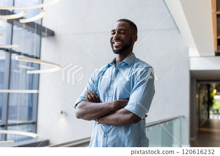 Smiling african american man in blue shirt standing with arms crossed in modern office Smiling african american man in blue shirt standing with arms crossed in modern office 120616232