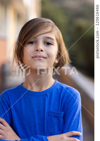 Smiling boy in blue shirt standing confidently with arms crossed outside school Smiling boy in blue shirt standing confidently with arms crossed outside school 120616466