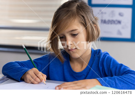 In school, focused boy writing with pencil on paper in classroom In school, focused boy writing with pencil on paper in classroom 120616478