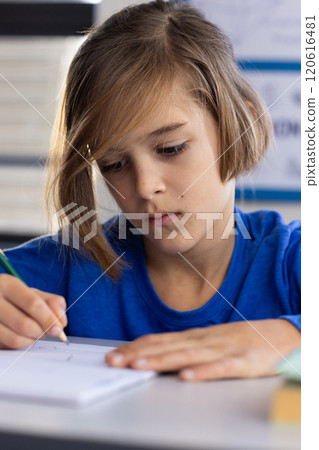 In school, focused boy writing in notepad during classroom activity 120616481