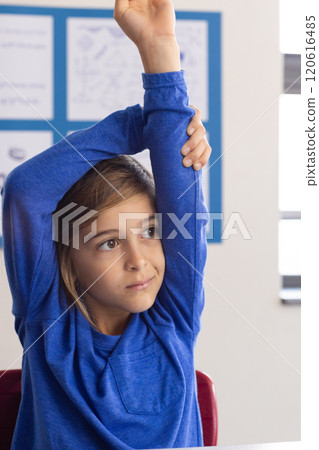 In school, boy raising hand in classroom, participating in lesson 120616485