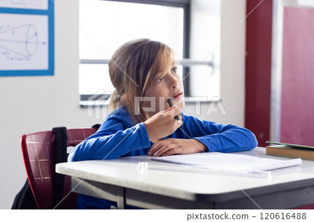 In school, boy sitting at desk thinking and holding pencil in classroom 120616488
