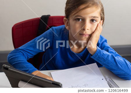 In school, boy using tablet and writing in notepad, looking at camera 120616499