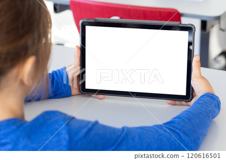 Holding tablet with blank screen, boy sitting at school desk, copy space 120616501