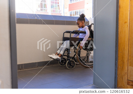 In school, african american girl in wheelchair moving through hallway, smiling and enjoying day In school, african american girl in wheelchair moving through hallway, smiling and enjoying day 120616532