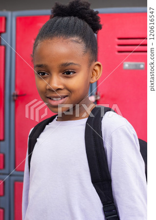Smiling african american girl with backpack standing in front of school lockers Smiling african american girl with backpack standing in front of school lockers 120616547
