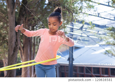 African american girl playing with hula hoop outdoors, enjoying physical activity at school African american girl playing with hula hoop outdoors, enjoying physical activity at school 120616581