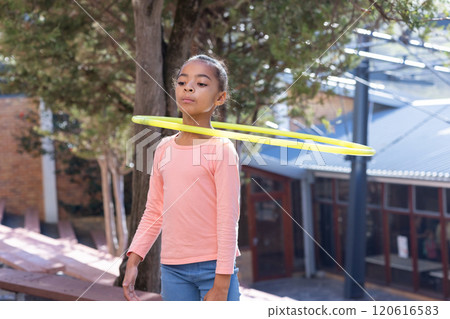 Hula hooping, african american girl in schoolyard enjoying outdoor activity during break Hula hooping, african american girl in schoolyard enjoying outdoor activity during break 120616583