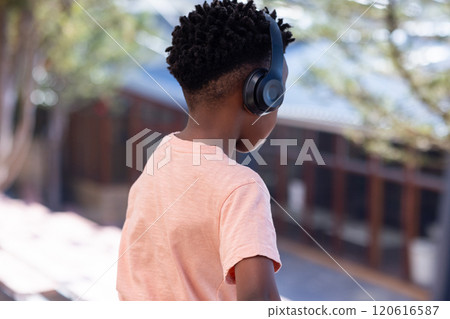 Wearing headphones, african american boy standing outside school building, listening to music Wearing headphones, african american boy standing outside school building, listening to music 120616587