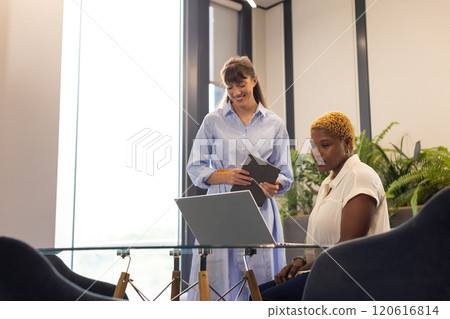 Collaborating in office, two women using laptop and digital tablet at desk Collaborating in office, two women using laptop and digital tablet at desk 120616814