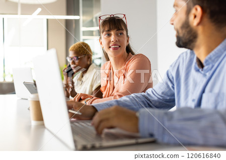 Working in office, colleagues using laptops and discussing project at desk Working in office, colleagues using laptops and discussing project at desk 120616840
