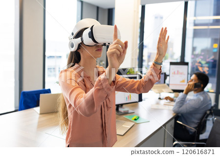 Using VR headset, woman interacting with virtual environment in modern office 120616871