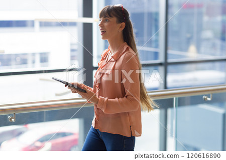 Holding tablet, woman walking and looking excited in modern office building Holding tablet, woman walking and looking excited in modern office building 120616890
