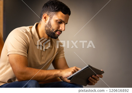Using tablet, man sitting indoors focusing on screen, copy space Using tablet, man sitting indoors focusing on screen, copy space 120616892