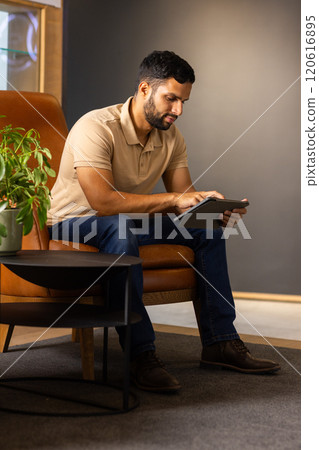 Using tablet, man sitting on chair and working in modern office Using tablet, man sitting on chair and working in modern office 120616895