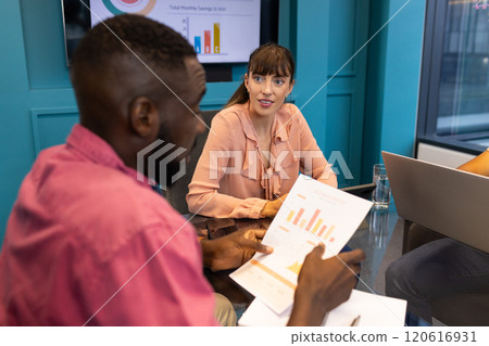 Discussing financial charts, colleagues collaborating in modern office meeting room Discussing financial charts, colleagues collaborating in modern office meeting room 120616931