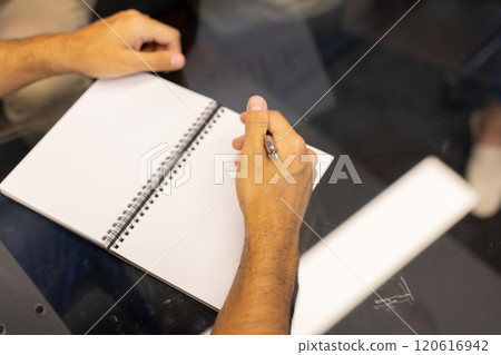 Writing in notepad, person taking notes during meeting at office desk 120616942