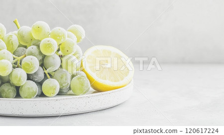 Frozen grapes with ice crystals paired with a fresh lemon wedge create a refreshing and healthy snack option Frozen grapes with ice crystals paired with a fresh lemon wedge create a refreshing and healthy snack option 120617224