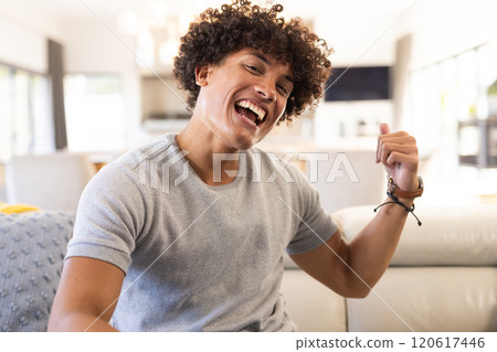 On video call, Smiling man sitting on couch, pointing, at home On video call, Smiling man sitting on couch, pointing, at home 120617446