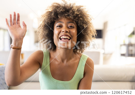 On video call, Smiling woman waving hand, at home 120617452