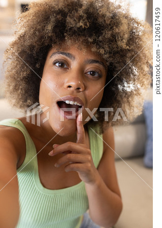 On video call, woman with curly hair making gesture, indoors, at home On video call, woman with curly hair making gesture, indoors, at home 120617459
