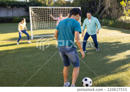 Playing soccer, family enjoying outdoor activity together on grassy field Playing soccer, family enjoying outdoor activity together on grassy field 120617553