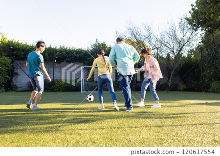 Playing soccer outdoors, family enjoying time together on green field Playing soccer outdoors, family enjoying time together on green field 120617554
