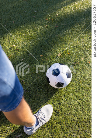 Kicking soccer ball on grass, person wearing sneakers and denim shorts 120617557
