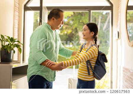 Welcoming daughter home from school, asian father smiling and holding her hands 120617563