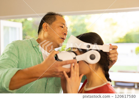 Adjusting VR headset, father helping girl experience virtual reality at home Adjusting VR headset, father helping girl experience virtual reality at home 120617580