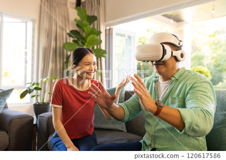 Using VR headset, father interacting while daughter smiling in living room 120617586