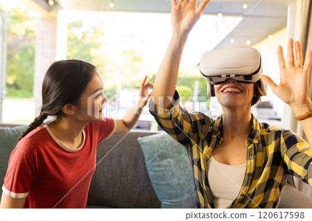 Using VR headset, mother enjoying virtual reality experience with daughter watching Using VR headset, mother enjoying virtual reality experience with daughter watching 120617598