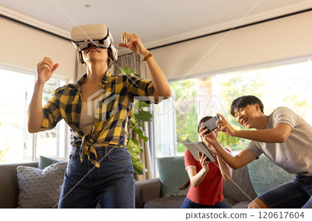 Using VR headset, mother enjoying virtual reality game with family at home Using VR headset, mother enjoying virtual reality game with family at home 120617604