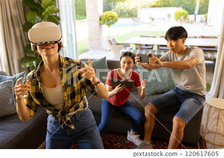 Playing virtual reality game using VR headset, mother with friends watching and recording Playing virtual reality game using VR headset, mother with friends watching and recording 120617605