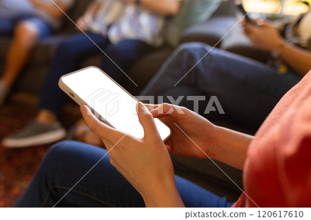 Using smartphone, person sitting on couch with family in living room, copy space 120617610