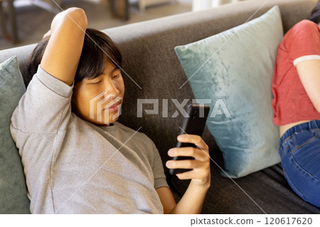 Relaxing on couch, young man browsing smartphone, enjoying leisure time 120617620