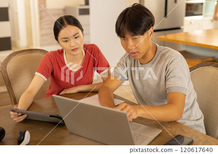 Using laptop and tablet, young asian brother and sister working together  at home 120617640