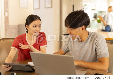 Discussing work, young asian brother and sister using laptop and tablet  at home 120617641